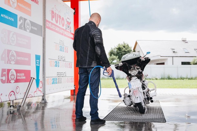 A man washing a motorcycle at PUTO self-service car wash during summer.