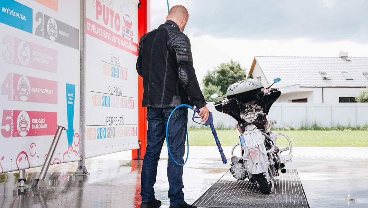 A man washing a motorcycle at PUTO self-service car wash during summer.