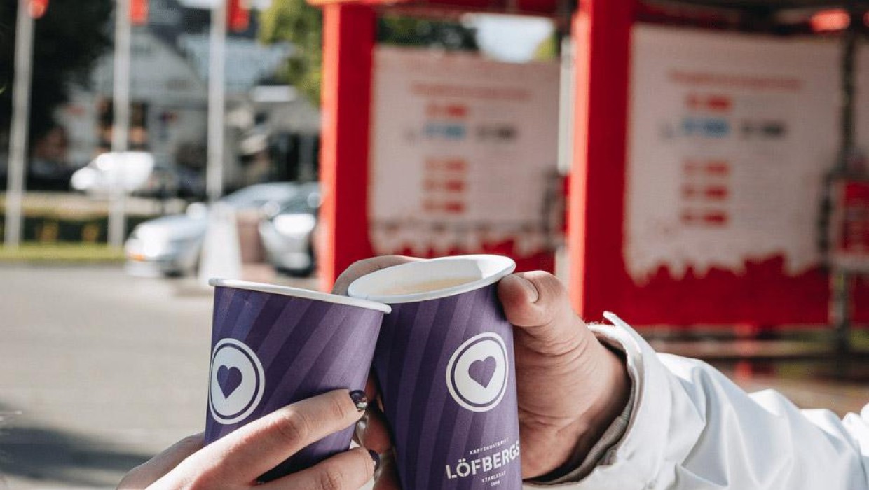 Two people holding LOFBERGS coffee cups at PUTO car wash.