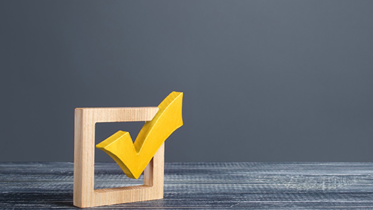 Yellow checkmark in a box symbolizing approval or selection on a gray background.